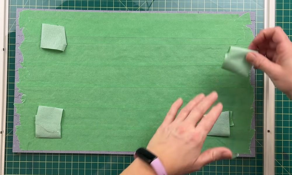 Back of a completed jigsaw puzzle secured with green tape inside a picture frame