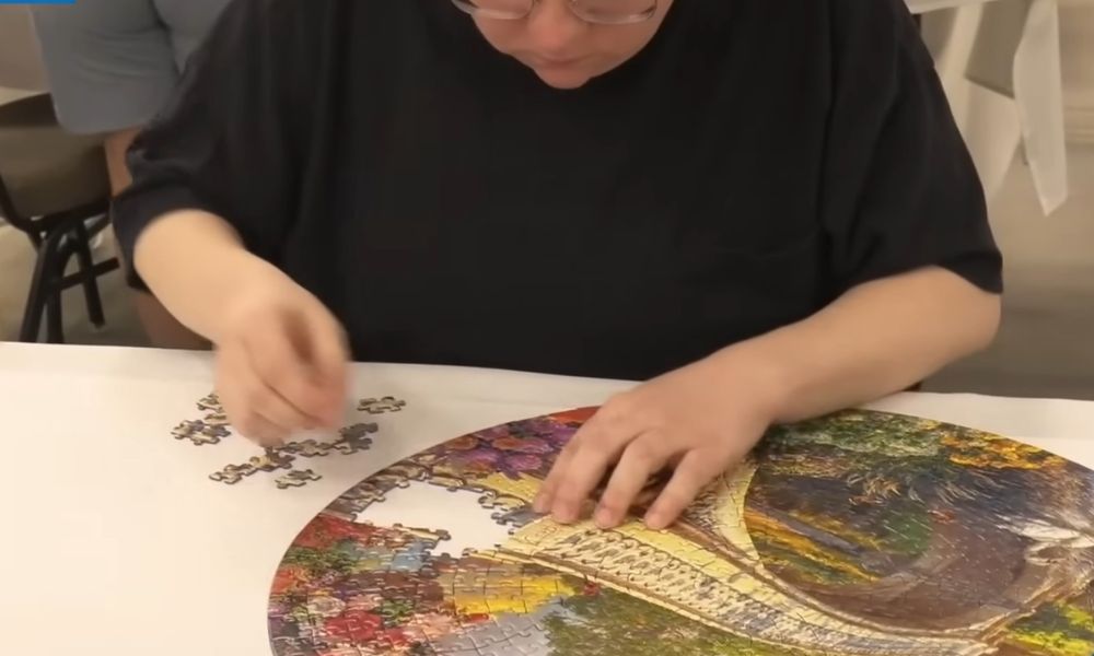 Speed puzzling competitor sorting loose pieces while assembling a colorful circular jigsaw puzzle