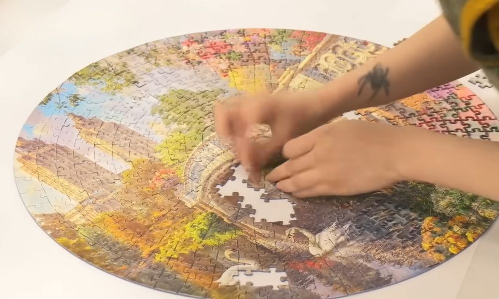 Close-up of hands assembling the center of a colorful round jigsaw puzzle during a speed puzzling competition.